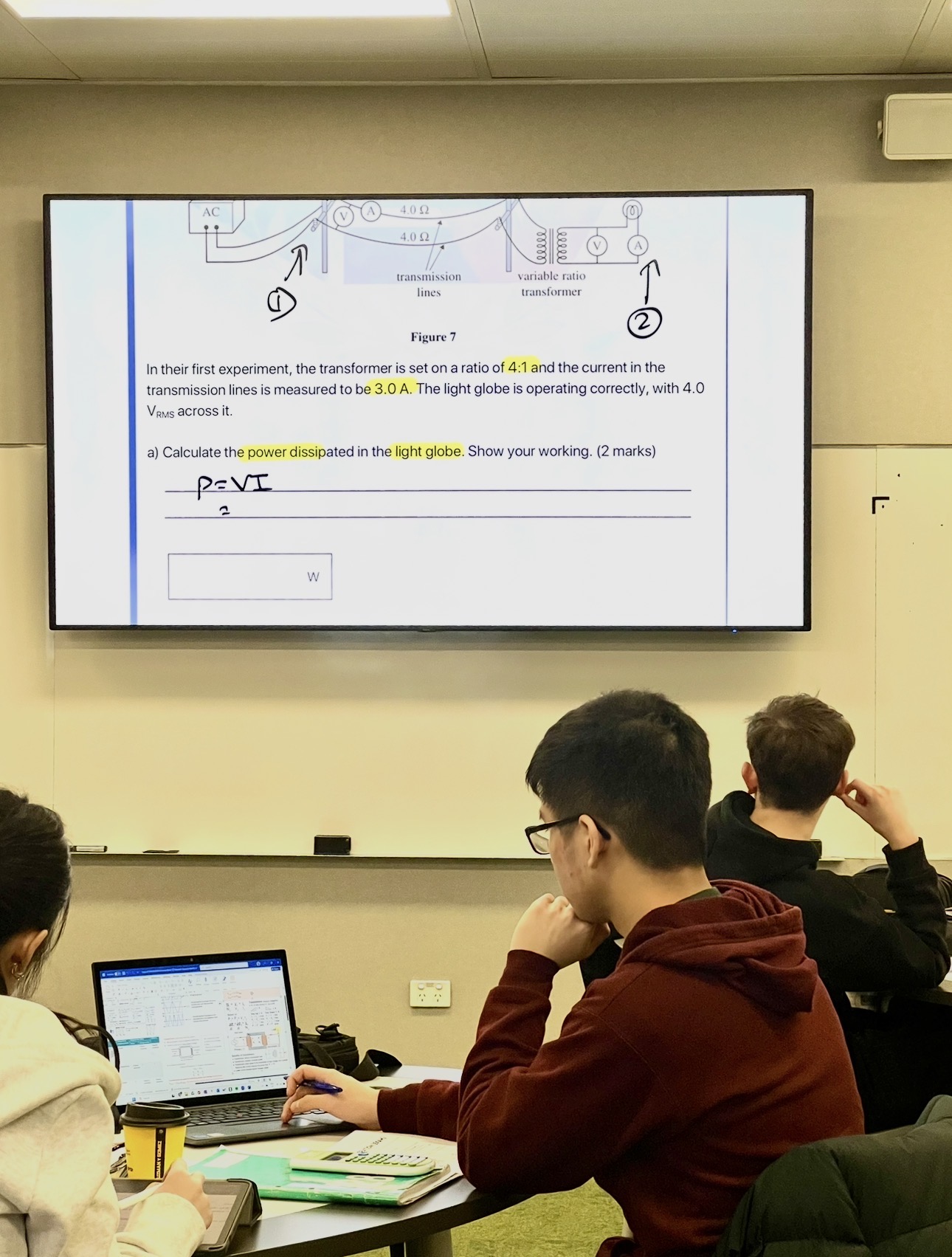 Student focused on a VCE Physics power generation exam question on screen